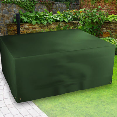 All-weather Rectangular Patio Set Cover - placed in a garden on grass with plants behind 